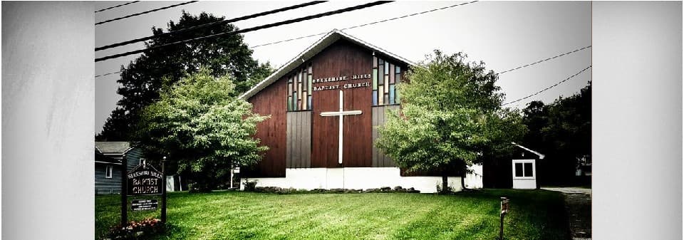 The Berkshire Hills Baptist Church building on Pleasant Street, with its wood siding and large white cross.